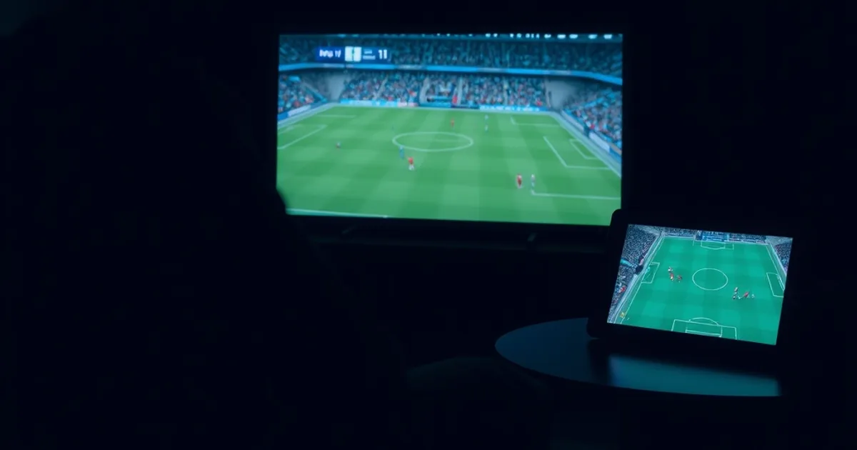 Dunkles Wohnzimmer, ein Zuschauer verfolgt gespannt ein Bundesliga-Spiel auf einem großen Bildschirm, im Hintergrund ein zweites Gerät mit Live-Fußball